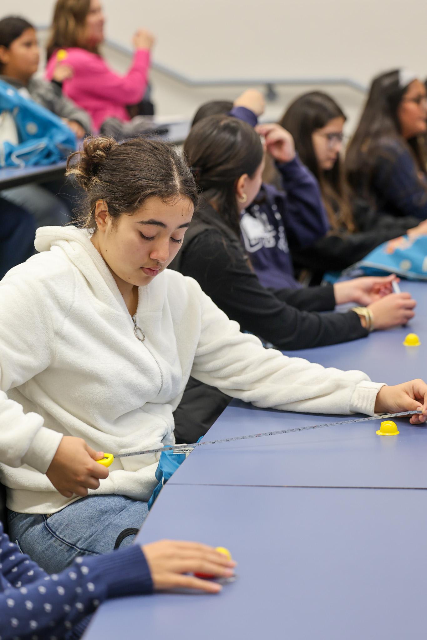 Student using measuring tape in science activity